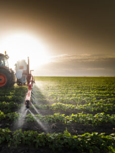Tractor spraying pesticides on soy field with sprayer at spring